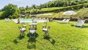 A poolside area with lounge chairs, umbrellas, and a table with chairs. - Marcigliana Cottage, Pool, Radicondoli (Radicondoli)