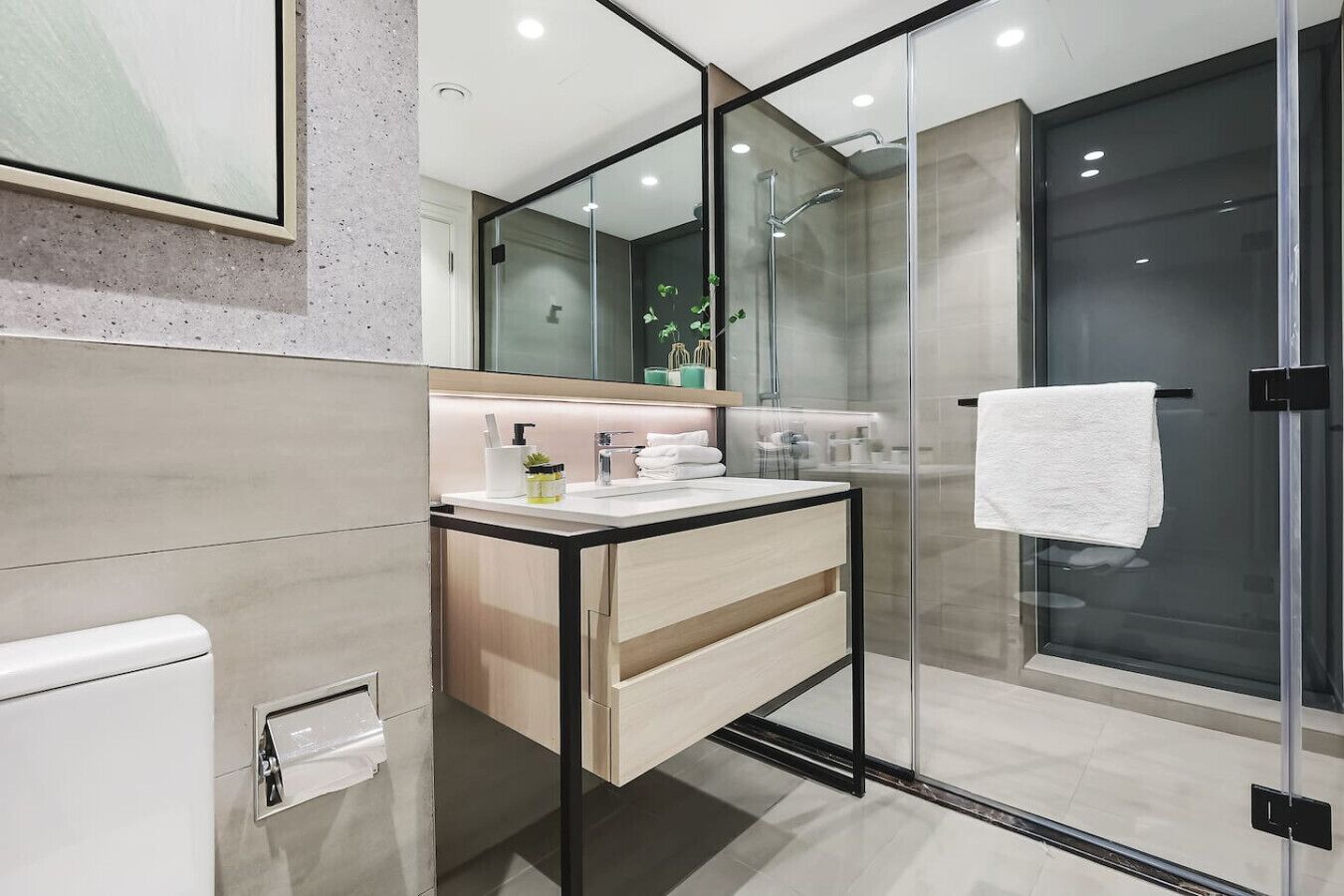 A modern bathroom with a glass shower enclosure, a white sink with a mirror, and a towel hanging on the door.