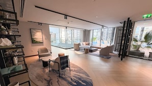 A spacious, modern hotel lobby with a large seating area, a coffee table, and a view of the city through large windows. - FIRST CLASS | 2BR | Serene Retreat in Wilton (Dubai)