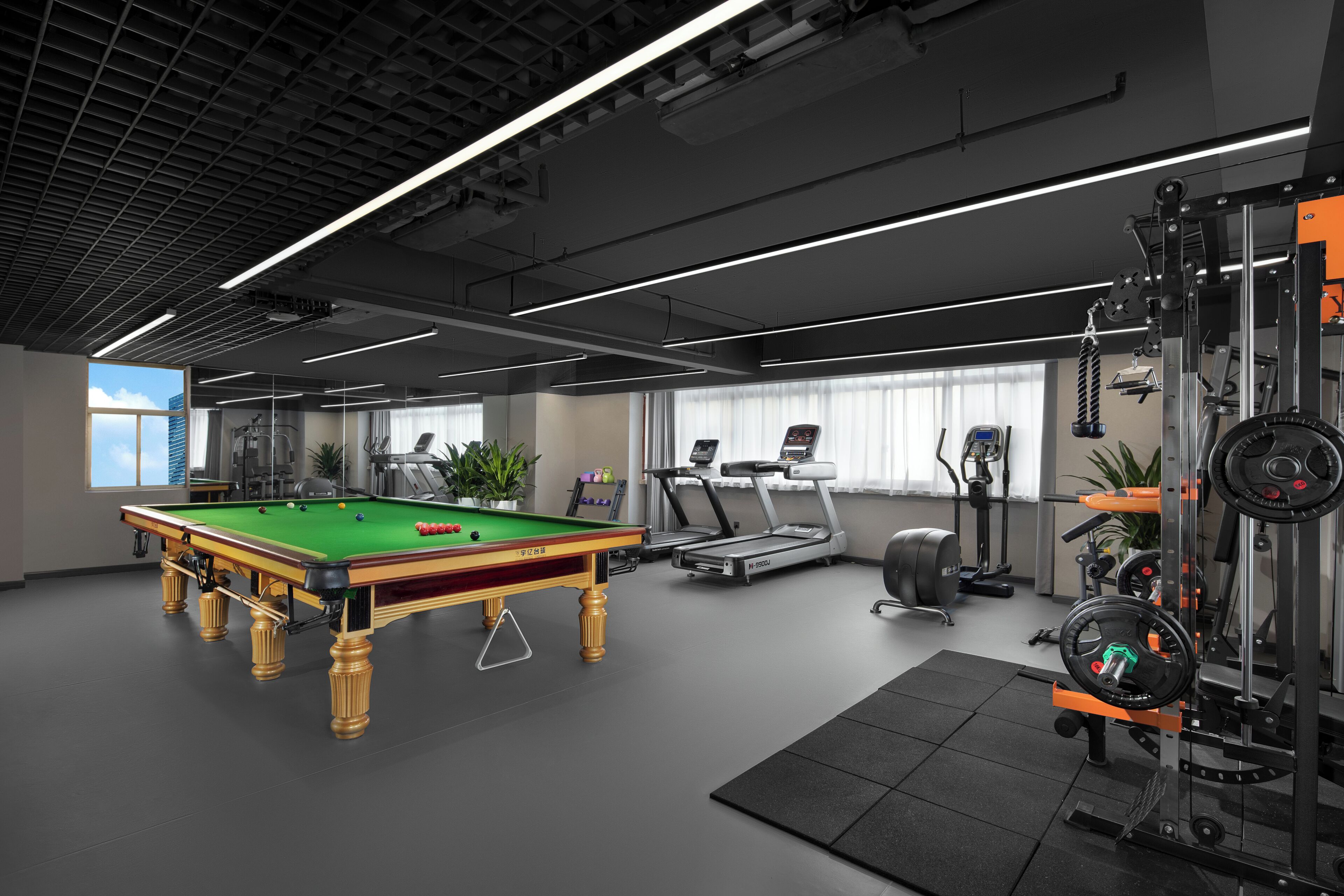 A modern indoor space with a pool table, exercise equipment, and a treadmill.
