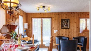 A wooden interior with a dining table set for a meal, a sofa, and two armchairs. - Dominic by Interhome (Nendaz)