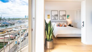 Ein Schlafzimmer mit einem Bett, einer Topfpflanze und Blick auf einen Yachthafen mit Booten.