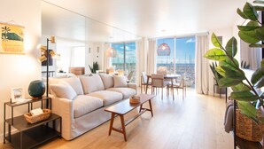 Ein modernes Wohnzimmer mit Sofa, Couchtisch und Essbereich, mit einem großen Fenster und Blick.