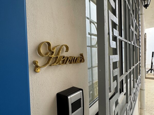 A building facade with a gold sign reading "Hotel" and a black intercom unit.