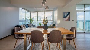 A modern dining area with a large table, six chairs, and a city view through large windows. - w* | Airy 2BR in San Francisco w/ Pool (Panamá)