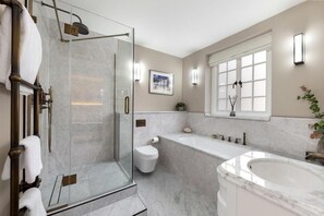 Ein modernes Badezimmer mit einer Glasdusche, einer freistehenden Badewanne und einer Toilette.