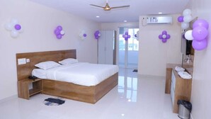 A bedroom with a wooden bed, a ceiling fan, an air conditioning unit, and a bathroom with a shower and toilet. - Sai Baba Palace Lodging and Boarding (Bidar)