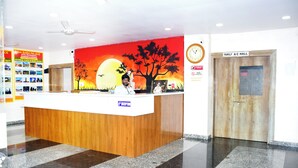 A hotel reception desk with a wooden counter, a clock, and a sign for the Family A/C Hall. - Sai Baba Palace Lodging and Boarding (Bidar)