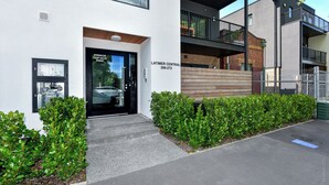 Un bâtiment moderne avec une façade blanche, une porte noire et une pancarte indiquant : « Vanne d’arrêt du système d’extinction automatique à l’intérieur ».