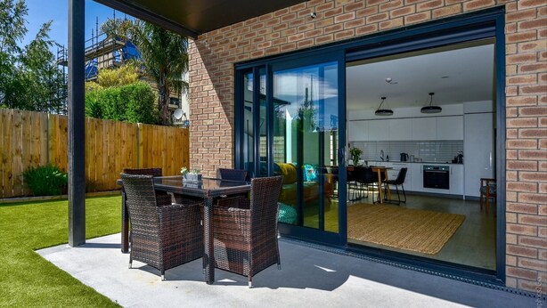 Une maison moderne dotée d’une porte coulissante en verre qui donne sur la cuisine et la salle à manger.