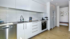 Une cuisine moderne avec des armoires blanches, des appareils en acier inoxydable et un plancher en bois.