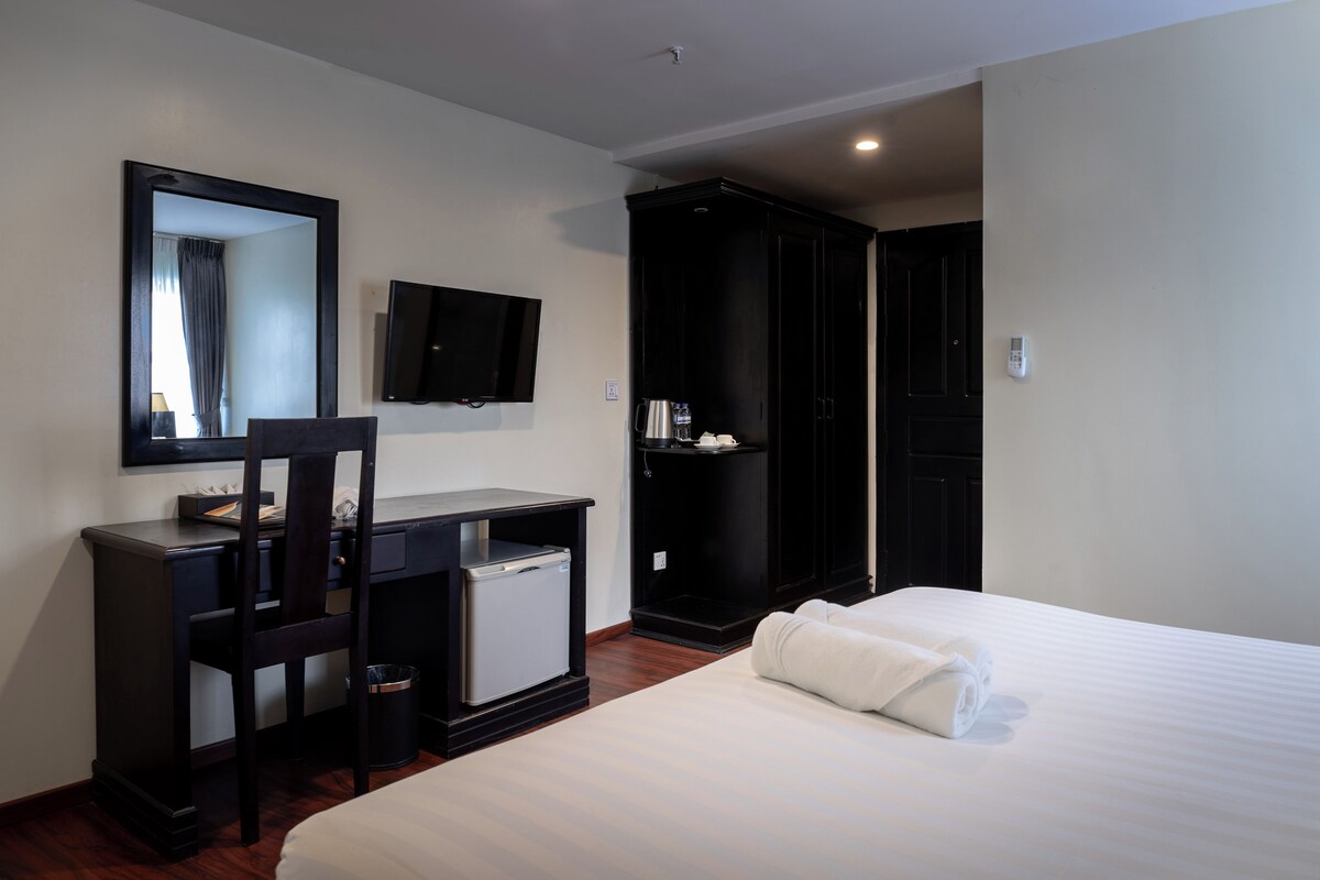 Une chambre d’hôtel comprenant un lit, un bureau avec un ordinateur, une télévision et une armoire.