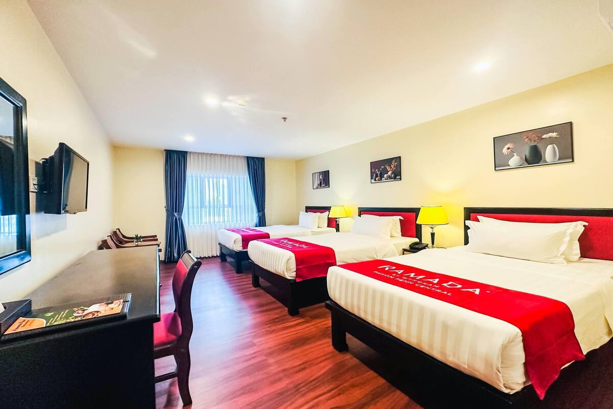 Une chambre d’hôtel avec trois lits, un bureau et un coin repas.