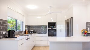 Una cocina moderna con armarios blancos, horno empotrado, microondas y refrigerador de acero inoxidable.