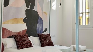 A modern bedroom with a bed, a large abstract painting, and a window with bars. - "Peral boutique Apartments: Cozy apartment in the center of Seville:  (Sevilla)