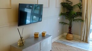 A modern living room with a flat-screen TV, a grey cabinet, and a potted plant. - "Peral boutique Apartments: Cozy apartment in the center of Seville:  (Sevilla)
