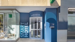A modern hotel entrance with a glass facade and a blue exterior. - zzzpace Smart-Hotel Krefeld (Krefeld)