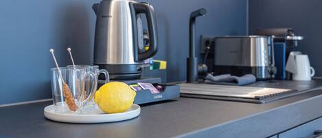 A modern kitchen with a coffee maker, a kettle, and a plate with a lemon.