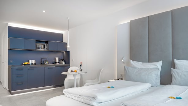 A modern hotel room with a large bed, a small kitchenette, and a seating area. - zzzpace Smart-Hotel Krefeld (Krefeld)