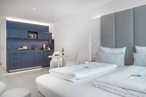 Una habitación de hotel moderna con una cama grande, una kitchenette pequeña y una zona de estar.