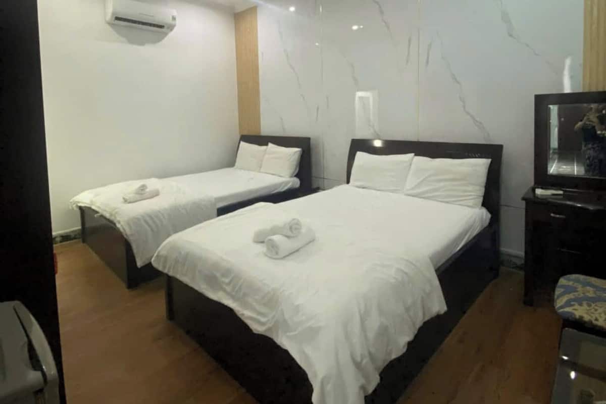 Une chambre d’hôtel avec deux lits, un téléviseur à écran plat et un système de climatisation.