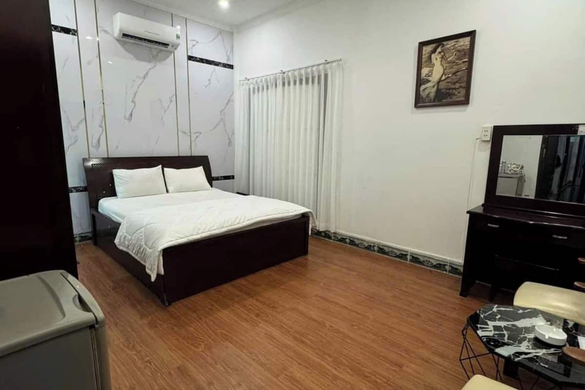 Une chambre d’hôtel comprenant un lit, un bureau, une chaise, une petite table et un miroir.