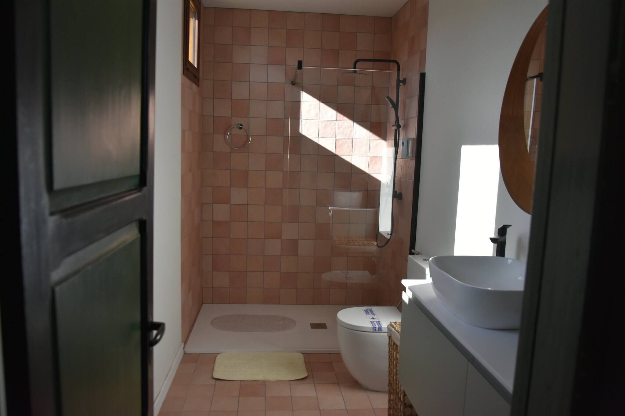 A bathroom with a shower, toilet, sink, and a mirror.