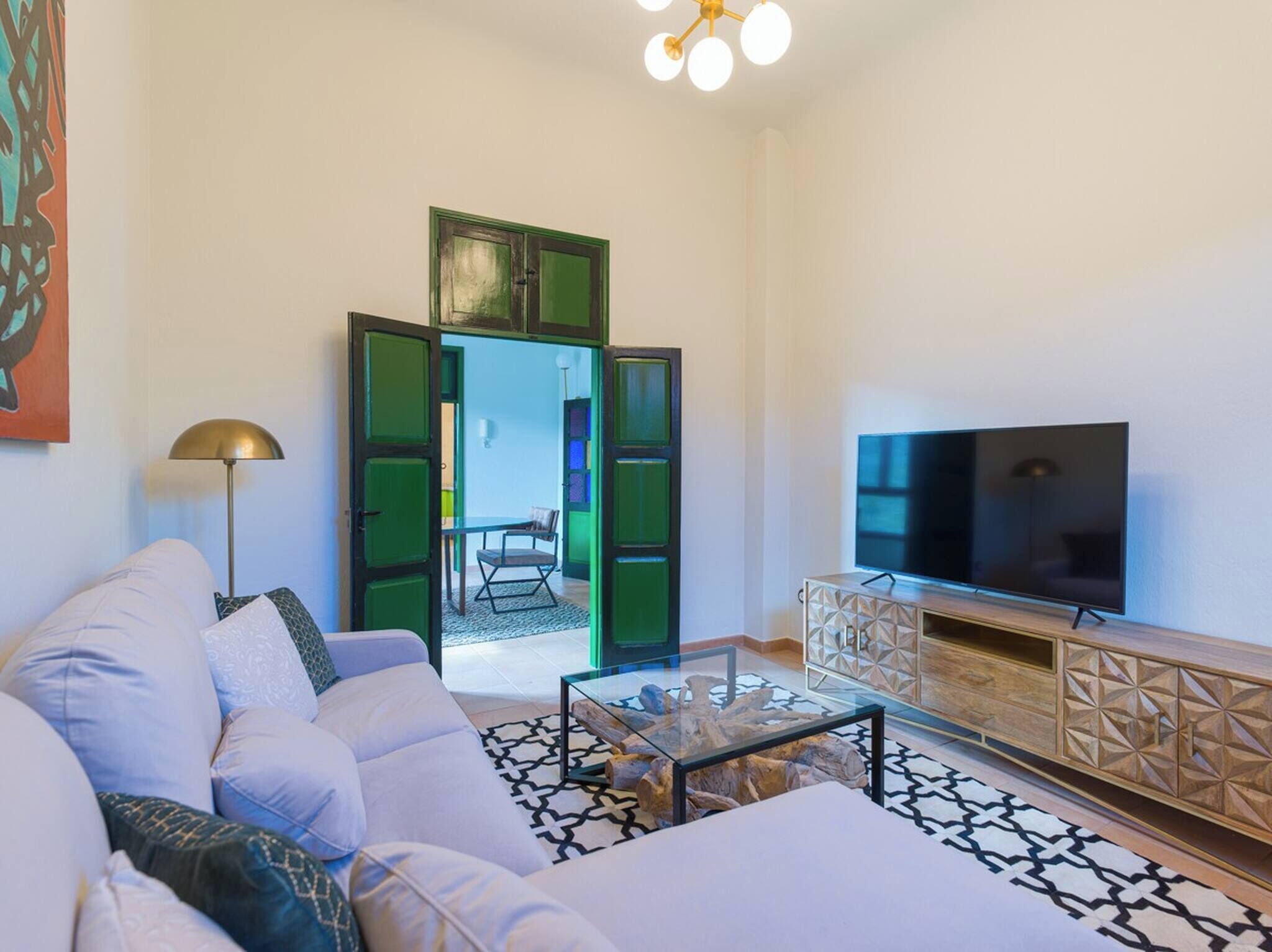 A modern living room with a white sofa, a glass coffee table, a TV, and a wooden cabinet.