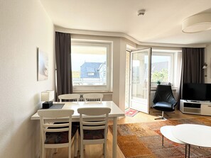 Relax in a comfortable seating area with a sofa, flat-screen TV, and dining space near a window with a view.