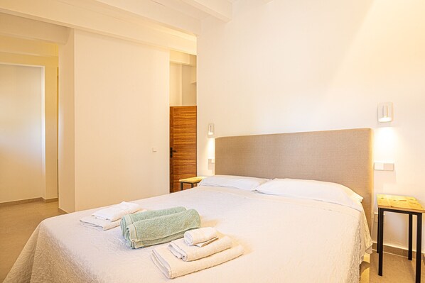 A hotel room with a large bed, a wooden headboard, and two bedside tables.