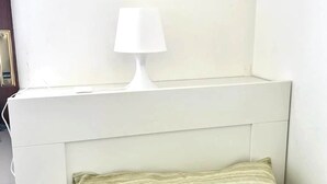 A white bedside table with a lamp, a headboard, and a pillow. - Brembate Comfort Home (Brembate)