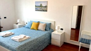 Une chambre à coucher avec un lit, des tables de chevet, un miroir et une chaise.