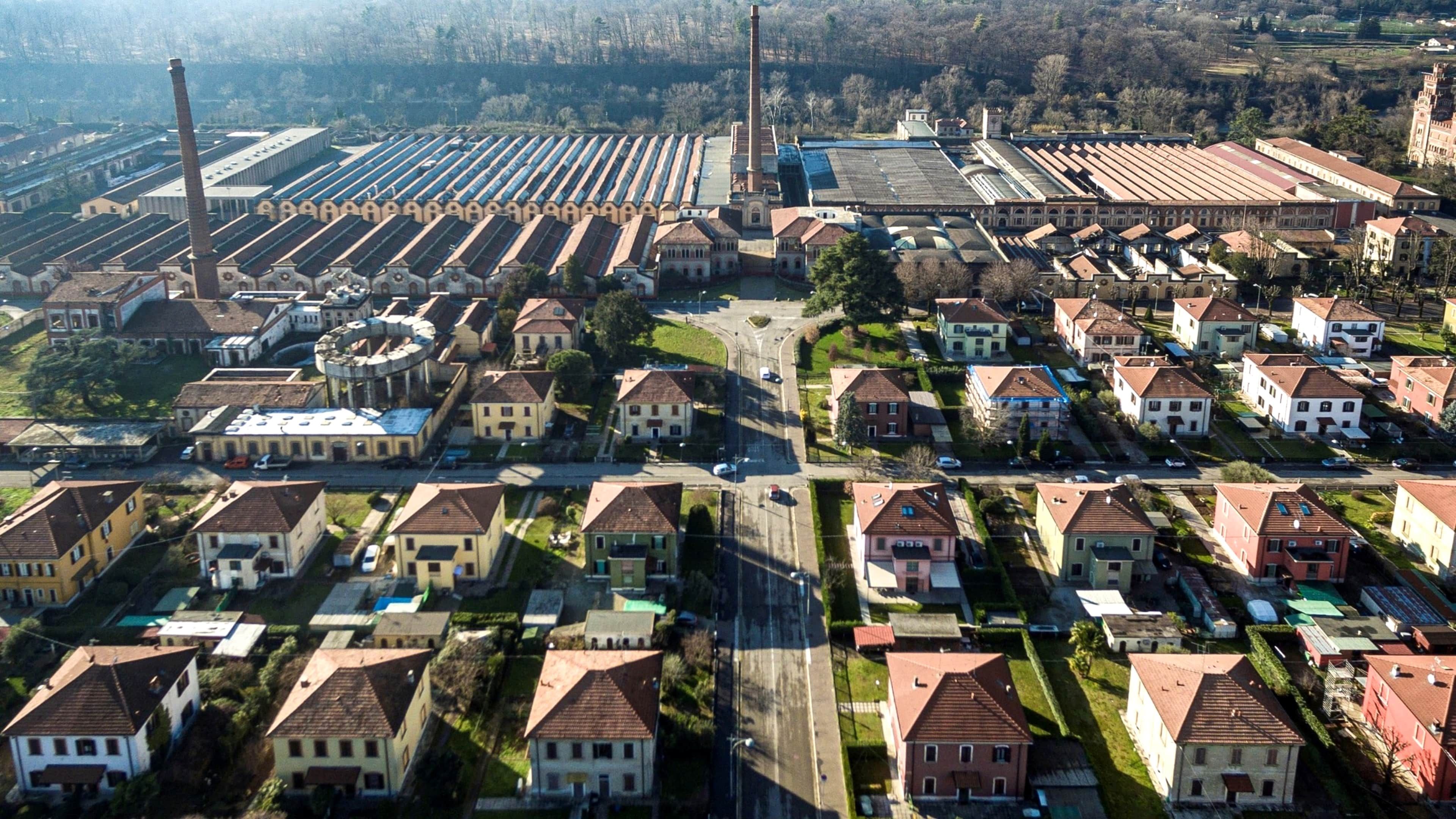 An aerial view of a residential area with houses, a large industrial complex, and a prominent church.