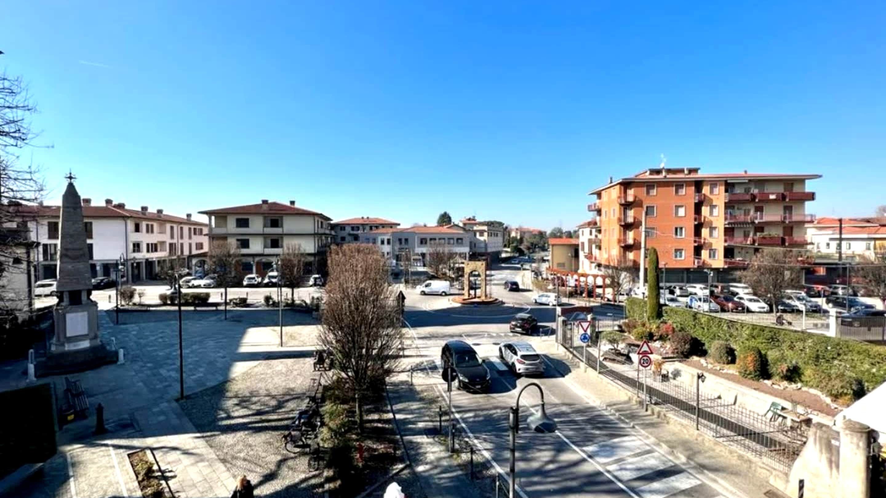 Ein Wohngebiet mit mehrstöckigen Gebäuden, einem Parkplatz und einem zentralen Denkmal.
