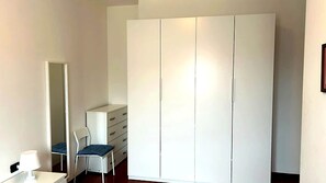 Een slaapkamer met een grote kledingkast, een stoel, een bureau en een spiegel.