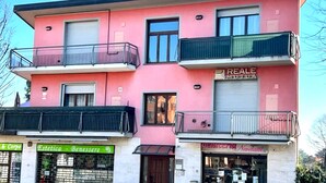 Un bâtiment rose doté de balcons, de devantures de magasins et d’une enseigne « REALE » bien visible.