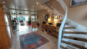 A spacious living area with a spiral staircase, a large rug, and a Christmas tree.