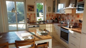 A kitchen with a dining table, chairs, a sink, a stove, and cabinets.