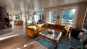A spacious living room with a large sectional sofa, a glass coffee table, and a dining area with a table and chairs.