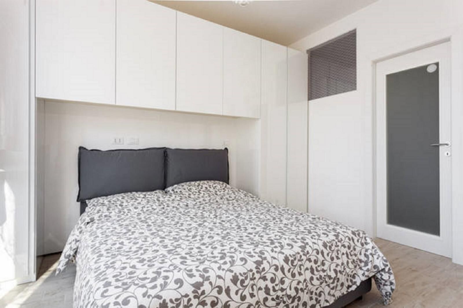 Ein Schlafzimmer mit einem Bett, einem weißen Kleiderschrank und einer Tür.