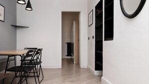 Un intérieur moderne avec une table à manger en bois, des chaises noires, un mur blanc et un miroir à cadre noir.