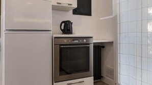 Une petite cuisine équipée d’un réfrigérateur, d’un four et d’une machine à café.