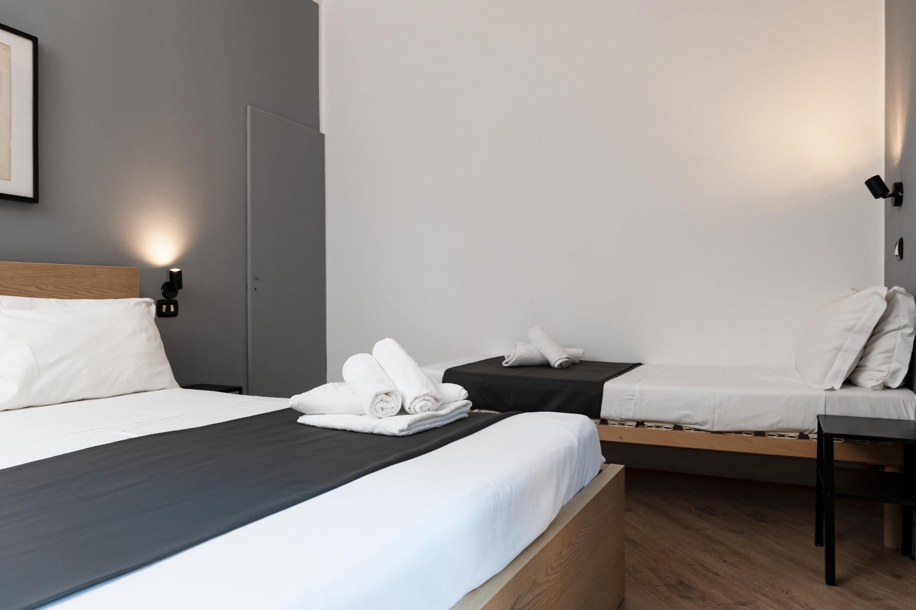 A hotel room with a large bed, a smaller bed, a desk, and a chair.