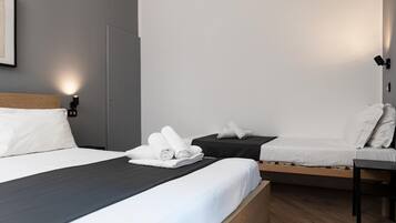 A hotel room with a large bed, a smaller bed, a desk, and a chair.