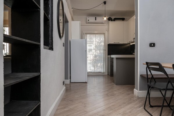 Une cuisine moderne avec des meubles blancs, un plan de travail noir et une table à manger en bois accompagnée d’une chaise.