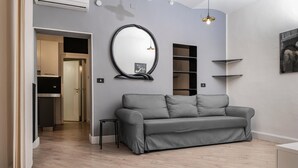 Un salon moderne avec un canapé gris, un grand miroir et une suspension.