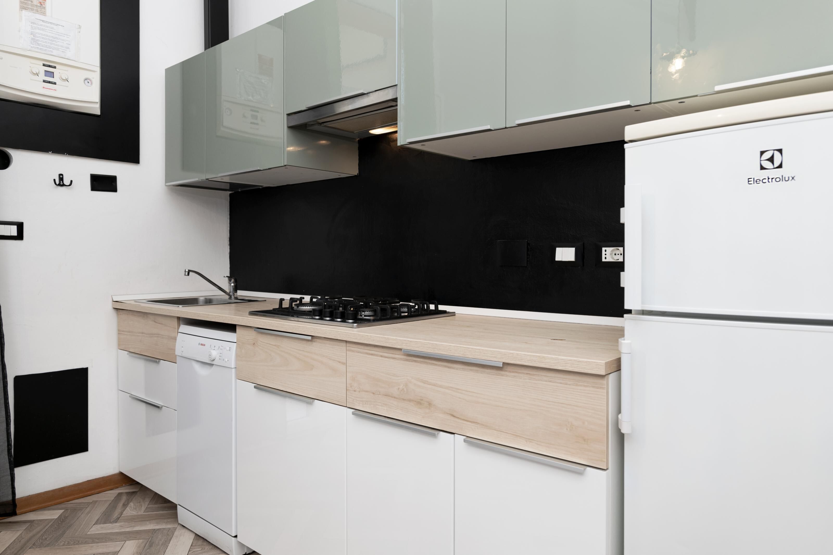 A modern kitchen with white cabinets, a Bosch dishwasher, a black stove, and an Electrolux refrigerator.