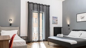 Une chambre d’hôtel moderne, équipée d’un lit, d’une chaise, d’une table, d’une fenêtre avec des rideaux et d’œuvres d’art accrochées aux murs.