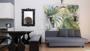 Un salon moderne avec un canapé gris, une table noire et un miroir.