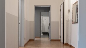 Un couloir doté d’un plancher en bois, de murs blancs et d’une porte donnant accès à une salle de bain.